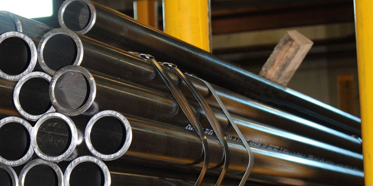 Marmon Keystone A stack of metal tubes is shown in a warehouse setting with the text “Marmon/Keystone Tube Pipe Bar IN STOCK,” highlighting our role as a leading supplychain distributor in metals.