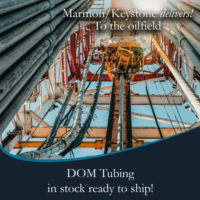 Marmon Keystone View looking up at steel pipes and equipment on an oil drilling rig, with text promoting Marmon/Keystone as your trusted metals distributor—with DOM tube and pipe in stock and ready to ship for oilfield supply chain needs.