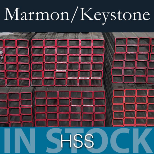 Marmon Keystone Stacks of rectangular hollow structural steel sections with red-painted edges are arranged in rows. The text above reads "Marmon/Keystone" and below reads "IN STOCK HSS metals distributor".